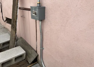 An electrical box next to a pink wall.
