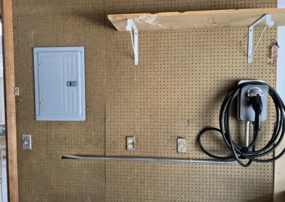 A garage with a pegboard wall and a power outlet.