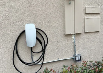 An electric car charger is attached to the side of a house.