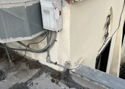 A white building with a red roof and wires.