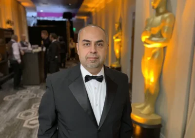 A man in a tuxedo standing in front of an oscar statue.