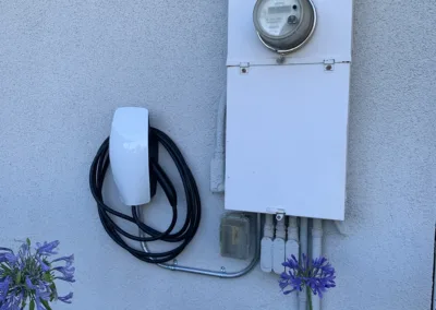 An electric car charger is attached to the side of a house.