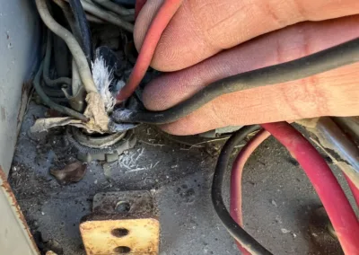 A person is removing wires from an electrical panel.