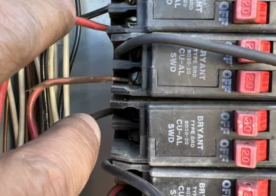 A person is putting wires into a circuit breaker.