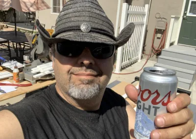A man in a cowboy hat holding a can of coors light.
