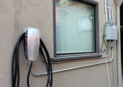 An electric car charging station on the side of a house.
